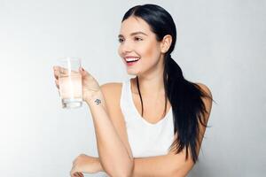 sorridente giovane donna con bicchiere di acqua foto