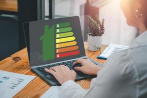 energia efficienza concetto, attività commerciale donna utilizzando il computer portatile computer su scrivania con energia efficienza icona su virtuale schermo. foto