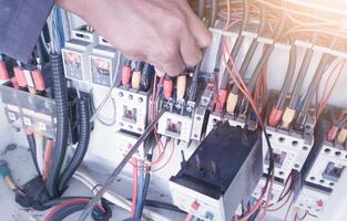il processi di riparazione elettrico componenti su il macchina controllo pannello, un elettricista usi un' Cacciavite per riparazione il elettrico controllo circuito serraggio.dei.componenti il terminali cavo potenza. foto