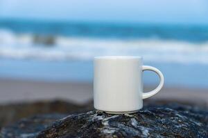 bianca caffè tazza su il roccia a mare. foto