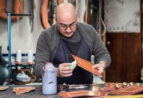 artigiano Lavorando il pelle nel il suo piccolo selleria laboratorio foto