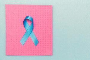 un' blu nastro nel supporto di mondo cancro giorno, raccolta il consapevolezza di persone vivente con un' prostata tumore. foto
