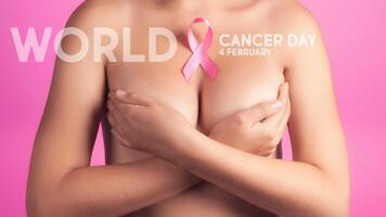 mondo cancro giorno concetto sfondo. giovane donna l'esame sua Seno per granuli o segni di Seno cancro. rosa nastro. foto