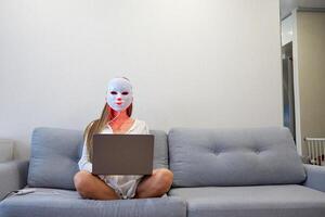 un' bellissimo ragazza con un guidato maschera su sua testa lavori a casa su un' il computer portatile. casa pelle cura concetto. foto