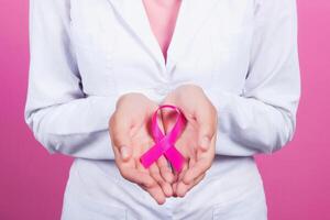 concetto della medicina e di sanità - le mani della donna che tengono il nastro rosa di consapevolezza del cancro al seno foto