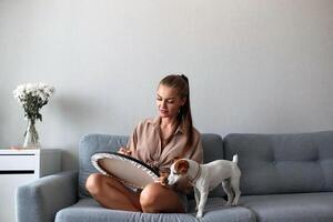 un' creativo femmina artista con un' cane è seduta e Lavorando su un' la pittura. un' contento giovane signora è pittura su tela nel sua appartamento. il concetto di un' giovane La madre di tempo libero foto