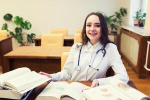 un' medico alunno per libri di testo. il studia di chirurgia di un' bellissimo ragazza nel il biblioteca foto