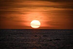 tramonto al di sopra di il baltico mare. il rosso sole affonda in il mare. sera atmosfera foto