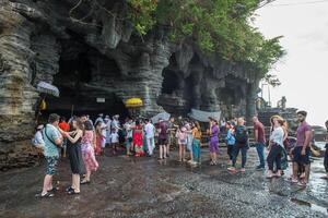 Bali, Indonesia - 16 luglio 2018 - molti turista in attesa nel coda per prendere il benedetto santo acqua a partire dal tanah lotto grotta. Locale persone creduto può portare sostentamento per chiunque chi Bevuto esso. foto