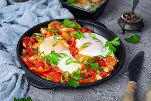 shakshuka con grigliato pane. fritte uova con pomodoro, Pepe, aglio e erbe aromatiche foto