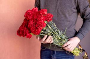 funerale mazzo di rosso garofani con nel il mani di un' uomo foto