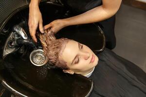 professionale parrucchiere tintura capelli di sua cliente nel salone. shampoo e lavaggio testa. selettivo messa a fuoco. foto