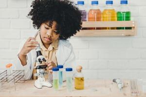 scienziato ragazzo giocare nel scuola scienza laboratorio kit. apprendimento formazione scolastica nero bambino ragazza sorridente. foto