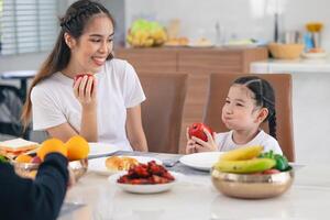 carino asiatico figlia mangiare rosso Mela frutta e salutare cibo con ragazza adolescente assistenza sanitaria stile di vita a casa foto