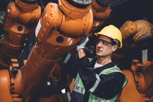 ingegnere squadra servizio fix robot saldatura braccio Lavorando nel automazione fabbrica. persone lavoratore opera nel robotica braccio montaggio pianta pesante metallo industria. foto