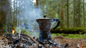 caffè è preparato nel un' scaldabagno caffè creatore su un' fuoco di bivacco nel il foresta. viaggio concetto foto