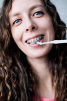 giovane donna spazzole sua denti con bretelle con un' monotrave spazzola, avvicinamento foto