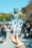 turista mostrare biglietto e visitare nel Kamakura, Kanagawa, Giappone. viaggiatore giro turistico il grande Budda statua. punto di riferimento e popolare per turisti attrazione vicino tokyo. Kanakawa, Giappone, 16 novembre 2023 foto