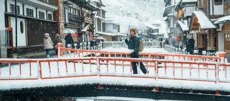 donna turista visitare ginzan onsen nel yamagata, contento viaggiatore giro turistico giapponese onsen villaggio con neve nel inverno stagione. punto di riferimento e popolare per attrazione nel Giappone. viaggio e vacanza concetto foto