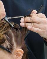 stilista taglio un' filo di capelli per un' cliente con professionale forbici. alto qualità foto