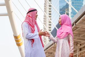 giovane arabo mezzo orientale uomo e donna tremante mani nel saluti, amichevole incontro foto