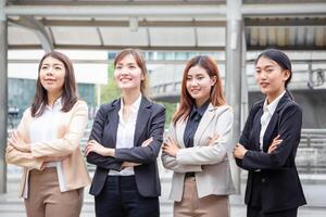 attività commerciale persone in piedi con braccia attraversato, giovane asiatico donne squadra in piedi con braccia attraversato sfocato città sfondo foto
