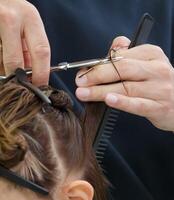 parrucchiere mani hold forbici e tagliare un' filo di capelli per il cliente. selettivo fuoco.alto qualità foto