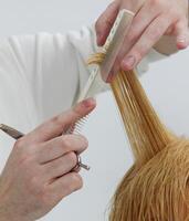 mani di invisibile parrucchiere con forbici e pettine quale detiene un' filo di il del cliente capelli. selettivo fuoco.alto qualità foto