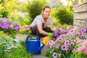 giardinaggio e agricoltura concetto. giovane donna azienda agricola lavoratore giardinaggio fiori nel giardino. giardiniere piantare fiori per mazzo. estate giardinaggio opera. ragazza giardinaggio a casa nel Giardino dietro la casa foto