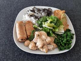 fatti in casa grigliato pollo con grigliato zucchine, verde insalata, primavera rotoli, riso pilaf e prezzemolo. broccoli semi su superiore di il riso pilaf. foto