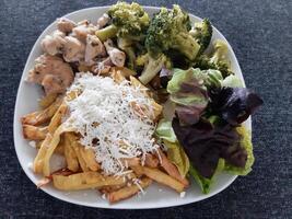 fatti in casa grigliato pollo con francese patatine fritte, broccoli, formaggio e verde insalata, servito su un' bianca piatto foto