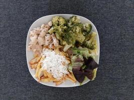 fatti in casa grigliato pollo con francese patatine fritte, broccoli, formaggio e verde insalata, servito su un' bianca piatto foto