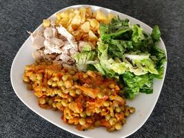 fatti in casa grigliato pollo con francese patatine fritte, verde insalata e pisello stufato servito su un' bianca piatto foto