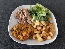 fatti in casa grigliato pollo con francese patatine fritte, verde insalata e pisello stufato servito su un' bianca piatto foto