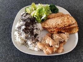 fatti in casa grigliato pollo con grigliato zucchine, verde insalata, primavera rotoli, riso pilaf e prezzemolo. broccoli semi su superiore di il riso pilaf. foto