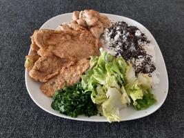 fatti in casa grigliato pollo con grigliato zucchine, verde insalata, primavera rotoli, riso pilaf e prezzemolo. broccoli semi su superiore di il riso pilaf. foto