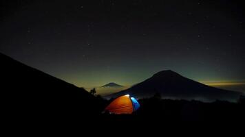 campeggio su un' montagna a notte viene visualizzato il bellezza di un' focoso montagna silhouette foto