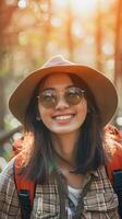 ai generato ritratto di un' giovane sorridente asiatico femmina indossare cappello e occhiali da sole campeggio nel natura, sfondo Immagine, generativo ai foto