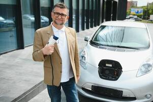 uomo addebiti un elettrico auto a il ricarica stazione foto