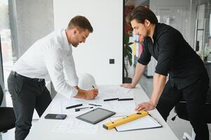 ingegnere o architetto lavoro di squadra Lavorando su costruzione progetto con edificio modello e planimetria nel ufficio. costruzione concetto. foto