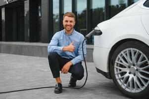 uomo addebiti un elettrico auto a il ricarica stazione foto