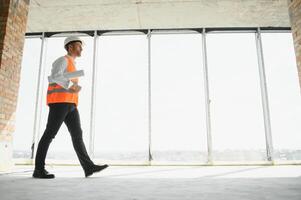 ritratto di uomo architetto a edificio luogo. fiducioso costruzione manager indossare elmetto protettivo. riuscito maturo civile ingegnere a costruzione luogo con copia spazio. foto