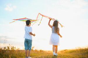 contento bambini lanciare un' aquilone nel il campo a tramonto. poco ragazzo e ragazza su estate vacanza. foto