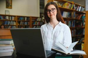 nel il biblioteca - bella femmina alunno con libri Lavorando nel un' alto scuola biblioteca. foto