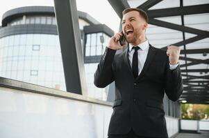 uomo d'affari sorridente e raccolta il suo cazzotto nel il aria, con ufficio edificio sfondo - attività commerciale successo, risultato, e vincere concetti foto