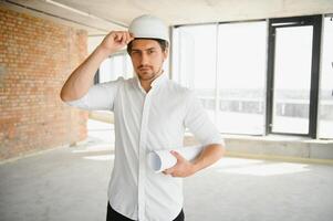 ritratto di uomo architetto a edificio luogo. fiducioso costruzione manager indossare elmetto protettivo. riuscito maturo civile ingegnere a costruzione luogo con copia spazio. foto