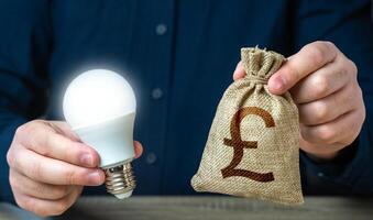 Britannico libbra sterlina i soldi Borsa e ardente idea leggero lampadina nel il mani di un' uomo. investimento nel un idea. offerta finanziario incentivi per valorizzare energia efficienza. ridurre carbonio orma foto