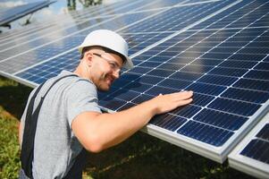 maschio lavoratore con solare batterie. uomo nel un' protettivo casco. installazione indipendente, autonomo solare pannello sistema foto