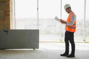 ritratto di un architetto costruttore studiando disposizione Piano di il camere, grave civile ingegnere Lavorando con documenti su costruzione luogo, edificio e casa ristrutturazione, professionale caposquadra a opera. foto