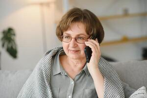 bello nonna parlando su il Telefono a casa. foto